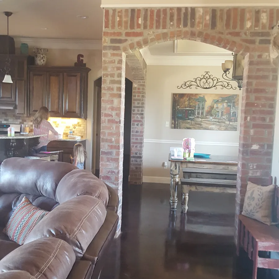 Open living area with old-brick arches leading to the dining room and kitchen, with stained concrete floors