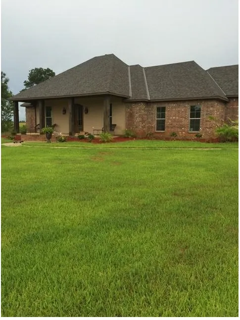 Single-story brick home with a hipped shingle roof and a covered entry, on a new lawn