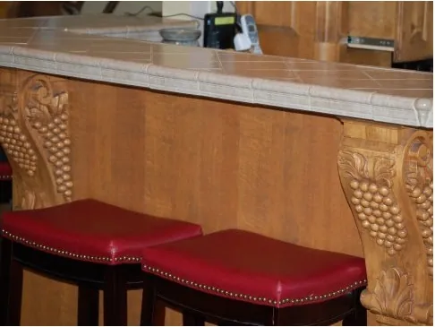Custom wood bar with hand-carved grape-vine corbels and red leather stools