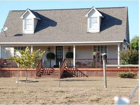 Cottage-style home with two dormers, a full front porch and a stained wood deck