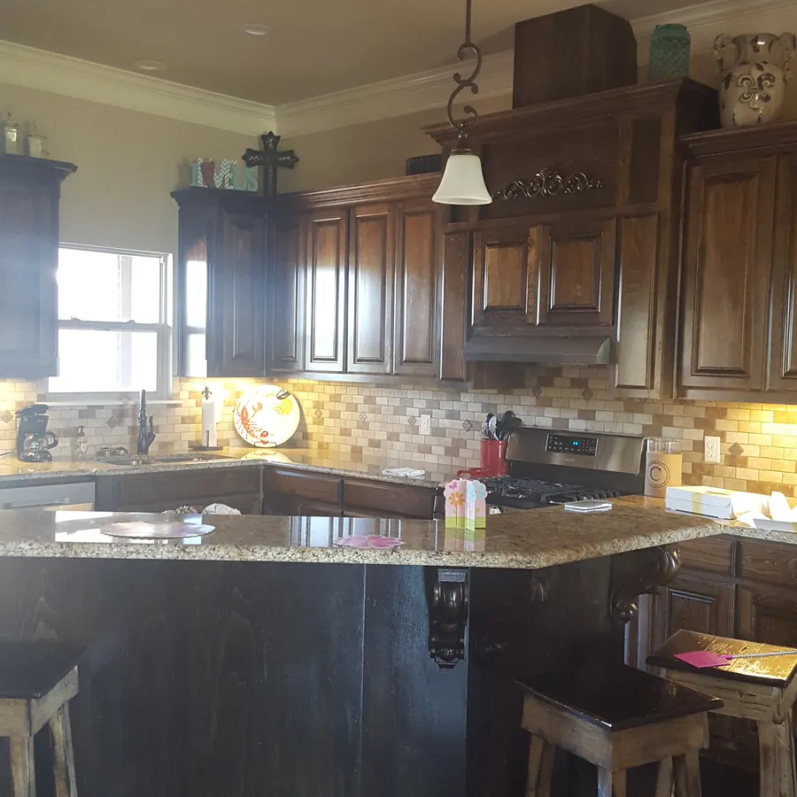 Kitchen with dark-stained raised-panel cabinets, carved corbels, granite counters and a tile backsplash